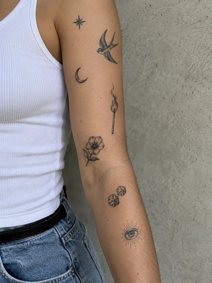 Patchwork collection of small black and grey charm tattoos on an adult arm